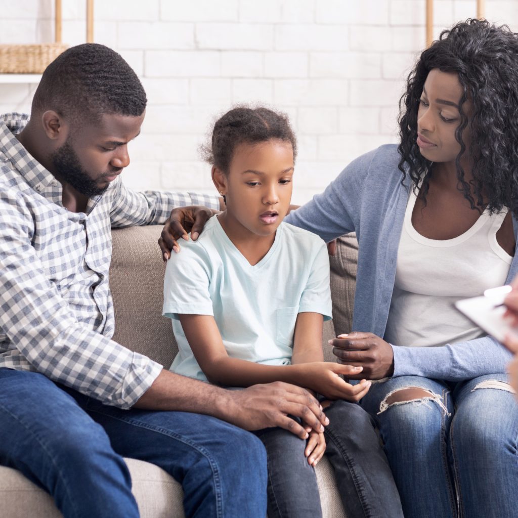 Little black girl and her parents at psychologist consultation